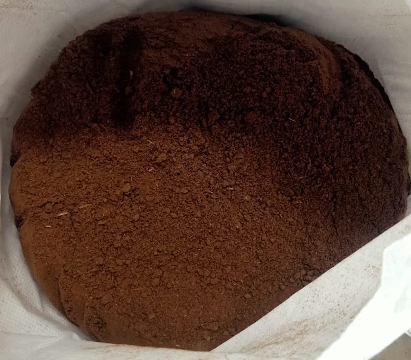 A photo of light brown, granular Chicken Meal powder in a scoop